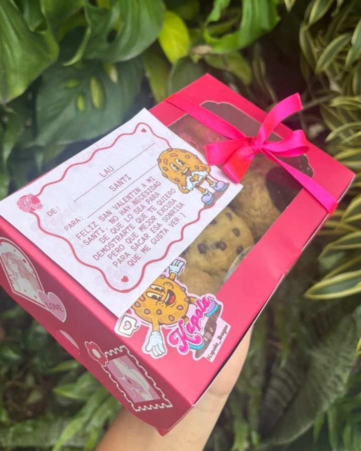 Caja de galletas Kapola con moño fucsia y tarjeta escrita de San Valentín